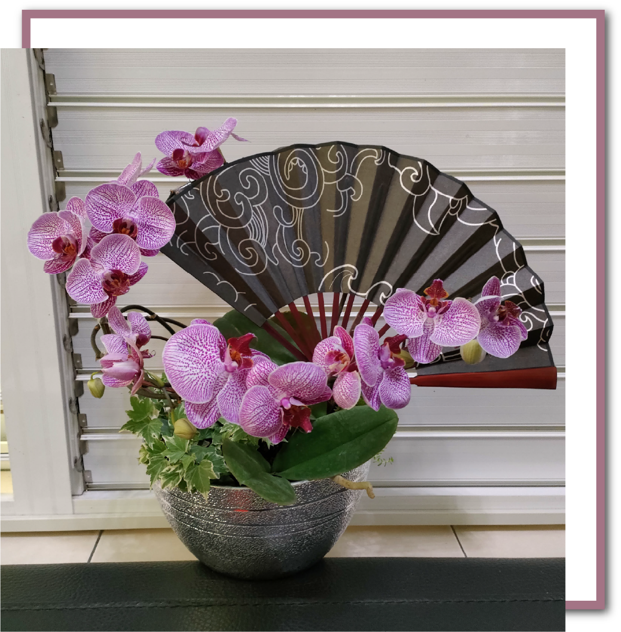 Elegant phalaenopsis orchid arrangement in silver textured ABS floral bowl with decorative Japanese-style folding fan – lightweight, durable plastic container for weddings, events, retail displays, and home décor.